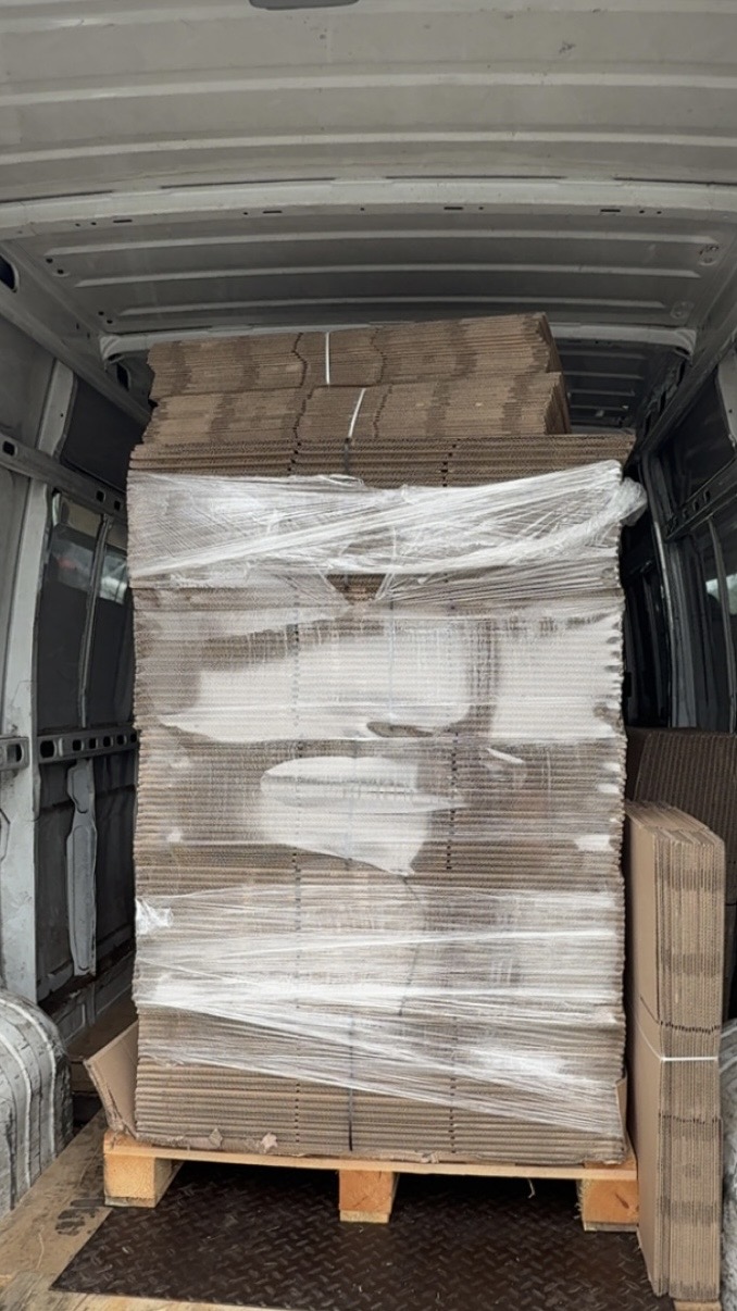 Paleta starannie zapakowanych kartonów w białym busie BiałyBus Przeprowadzki